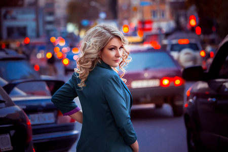 Beautiful stylish woman in a yellow coat and hat with long walks through fields autumn city, business women, lady in the city, creative computer colors, fashionable toningの写真素材