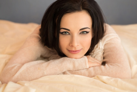beautiful girl in a transparent blouse sitting on the bed and smiling cute , fashionable toning , creative colorの写真素材