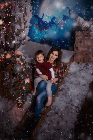 little girl smiles and enjoys the snow sitting by the mother's arms bear , happy childhood , fashionable toning , creative colorの写真素材