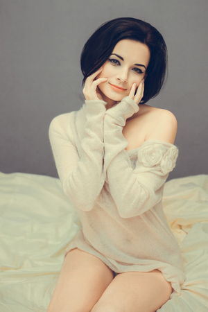 beautiful girl in a transparent blouse sitting on the bed and smiling cute; fashionable toning; creative colorの写真素材