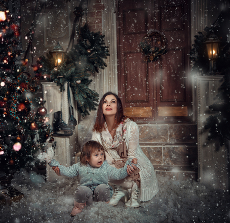 little girl smiles and enjoys the snow sitting by the mother's arms bear , happy childhood , fashionable toning , creative colorの写真素材