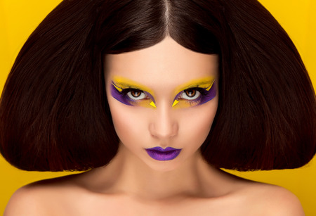 The avantaged portrait,girl with an unusual make up looking at the camera,portrait on a yellow backgraund,custom volume hairstyle metal ornament in the form of fragments,fashionable toning,creativeの写真素材