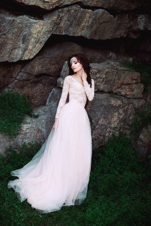 The girl in transparent pastel dress with a train, with a tiara in her hair. Fairy stands on top of the green hills, Creative fashionable color toningの写真素材