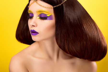 The avantaged portrait,girl with an unusual make up looking at the camera,portrait on a yellow backgraund,custom volume hairstyle metal ornament in the form of fragments,fashionable toning,creativeの写真素材