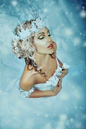 Luxurious lady in a white dress standing in  a snowy forest , Snow Queen, a fantastic shot,a fashionable toning , creative colorの写真素材