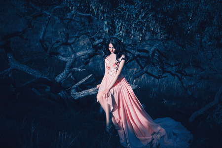 Lady in a luxury lush pink pastel dress   near the tree,fantastic shot,fairytale princess is walking in the autumn forest,fashionable toning,creative computer colorsの写真素材