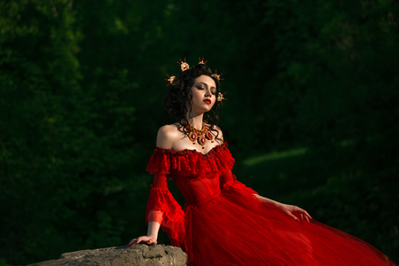 countess in a long red dress  is walking in a green forest full of branches, elf,  Princess in vintage dress, the queen of the forest,fashionable toning creative computer colorsの写真素材