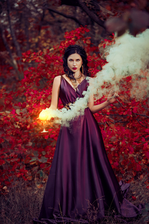 Lady in a luxury lush purple dress ,fantastic shot,fairytale princess is walking in the autumn forest,fashionable toning,creative computer colorsの写真素材