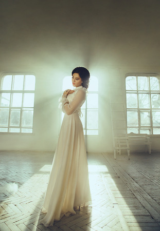 Lady in white vintage dress standing in a large spacious room, fantastic shot, fairytale princess turned into smoke, trendy toning, creative computer colorsの写真素材