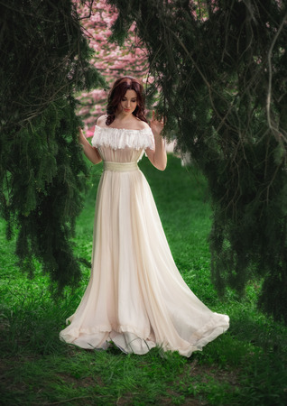 beautiful spring walk in the woods among the  cherry blossom in Aprila lady in a long dress pastel , creative computer colors, fashionable toningの写真素材