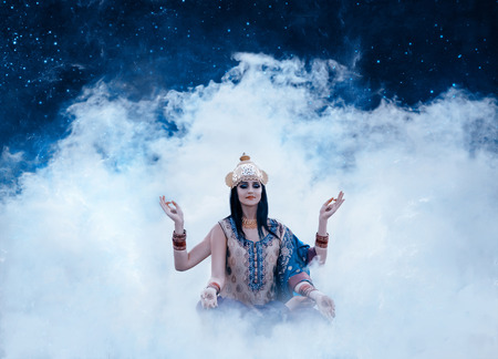 beautiful east exterior girl sitting in the smoke depicting eastern deity, indian, shiva, fashion creative color toningの写真素材