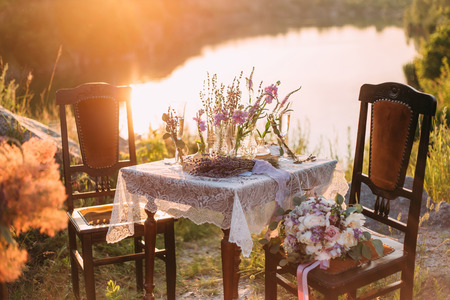 Photo table with chairs.Decor for an unusual photo shoot.Beautiful landscape.A bouquet of wild flowers in Provence style.Fashion toning.Creative color.の写真素材