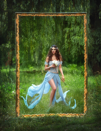 The picture is fantastic lady, luxurious, fancy dress. Mysterious Flirty fairy walks in the woods. Mythical white flower in his hands. Lovely long legs. Beautiful hair accessory handmade. Picturesque landscapes of the outdoors.Toning fashion. Creative colの写真素材