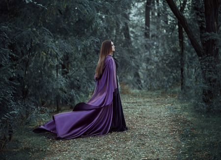 On the eve of Halloween witch casts a spell, decided to collect the potion to cook, walk in the mysterious forest. Fabulous and mystical concept. Fantastic shooting in the wild. Fashionable toning. Creative color.の写真素材