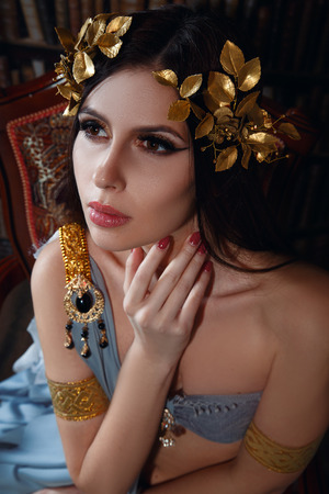 Luxury brunette in wreath of leaves. Portrait of a woman in Greco-Roman attire. Bohemian style. Fantastic shooting. Fashionable toning. Creative color.の写真素材