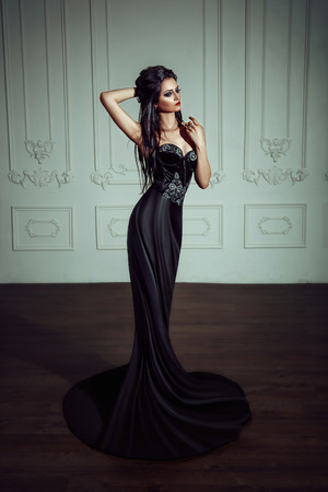 Beautiful brunette girl in a luxurious, black dress. Indian woman in the role of a chess piece. Black queen.の写真素材
