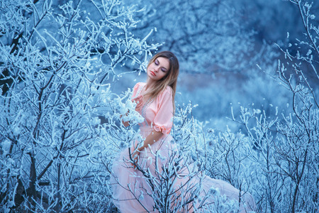 Fabulous walks in winter forest girl in a long dress of pastel colors.Melancholy mood, sadness, dreams.Bizarre snow patterns on trees branches.Fantastic shooting.Fashionable toning.Creative color.の写真素材