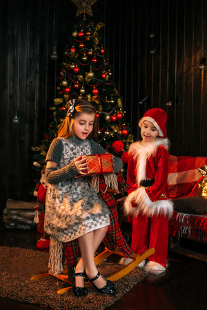 Little Santa brings gifts for  beautiful girl. Christmas funny story. The festive mood. Creative colors.の写真素材