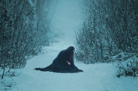 The girl a demon walks alone. She is wearing a long, black traveling cloak.の写真素材