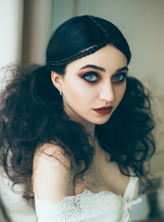 Girl with huge blue eyes posing on camera. Creative hairstyle with a strong fleece. Make-up of the color of Marsala.の写真素材