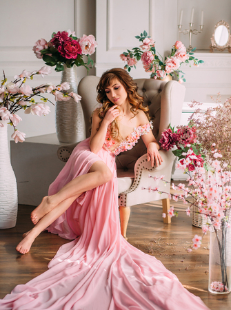 Young woman and many flowers. Princess in a pink dress. Creative colorsの写真素材