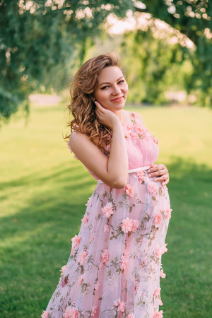 Cute woman in a beautiful dress with a flowers. Fantastic picture of pregnancy. Creative colors.の写真素材