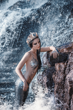 The real mermaid is resting on the ocean shore. Silver tail, the body is covered with scales. Creative colorsの写真素材