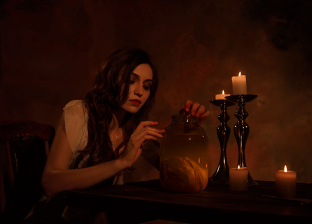 A beautiful, proud, heartless lady in a white vintage nightie. It stands on the background of a bloody wall and keeps her heart in the bankの写真素材