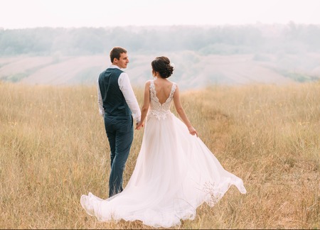 Wedding day. Stylish young couple walking on a background of wildlife at sunset. Fines Photoの写真素材