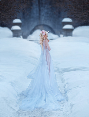 A wonderful creature, a unicorn girl in a light, white, slightly transparent dress, walks through the snow. The background is a frosty winter. Artistic Photographyの写真素材