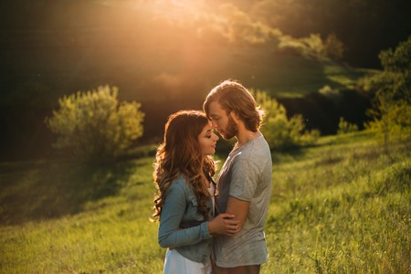 Stylish young couple. Film photo with a light and a sunlight. A guy with a stylish haircut and a red-haired girl. The withered ones touch each other sensually, face to face, with their eyes closedの写真素材