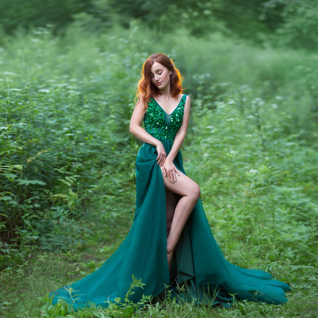 a red hair witch in green dress with long trainの写真素材