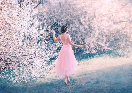 pretty slender girl with braided dark hair walks in garden barefoot, forest princess goes to sun, lady in delicate elegant pink dress with deep neckline on back, fantastic character, creative colorsの写真素材