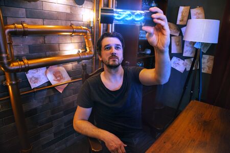 Portrait of a young man in a steampunk scientistâ€™s office. The doctor holds in his hands a...