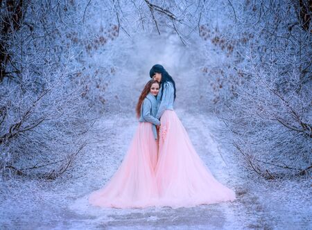 Happy mom hugs daughter in fabulous winter forest. Queen long black hair, princess brunette . Family...