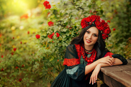 Close-up portrait Ukrainian happy girl looks at camera. Authentic woman smiling face. National ethnic vintage costume black dress stylish vyshyvanka. Wreath crown on head red flowers roses, poppiesの写真素材