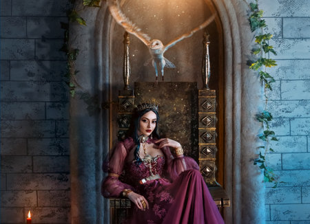 Art photo real people fantasy woman evil elven queen sits on throne, dark magic purple long dress Sexy face witch elf girl. Gothic vampire princess, crown. Barn owl fly flaps wings. halloween costumeの写真素材