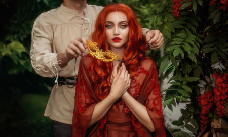 Fantasy portrait romantic couple in love man and woman, medieval style masquerade ball. gold carnival mask. Red-haired sexy girl lady queen. Guy king face cropped. Vintage white shirt. Summer nature.の写真素材