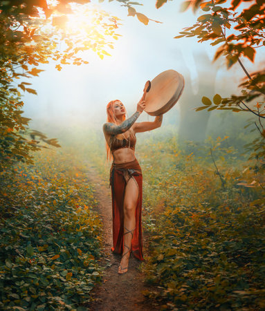 Art photo real person fantasy woman shaman holds drum in hands, plays music beats out mystery melody. Magic mystical forest green grass trees fog sun divine light. Woman Viking Nordic brown red dressの写真素材