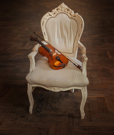 wooden violin lies on armchair old vintage style, classic furniture royal throne chair white fabric...