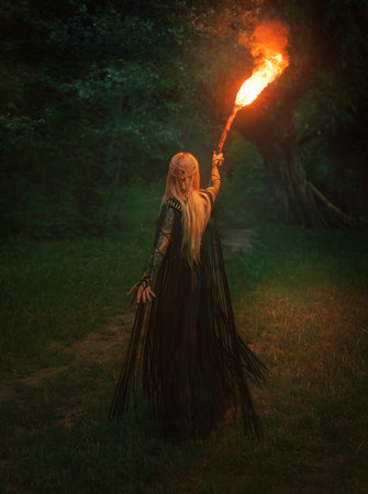 Gothic fantasy woman walking in mystical dark foggy forest holding burning torch in hands, bright...