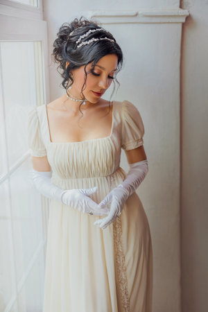 art photo real person fantasy portrait beautiful woman standing by window, white dress vintage old style. Sexy lady girl waiting love. dark hair hairstyle, evening make-up face lips eyes 19th century.の写真素材