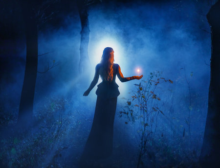 art photo real person beautiful fantasy woman holding magic light in hands, glowing ball fly in air illuminates way in dark night forest fog tree. Girl elf magician dress. mystic lady sorceressの写真素材