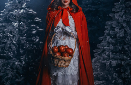 gothic woman queen walking in dark night forest tree winter cold nature snow falling, fairy tale lady Fantasy girl princess witch hands holding basket of apples. red cape white dress. moon light fogの写真素材