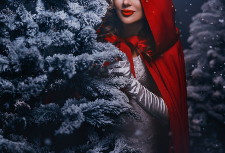 cropped beauty face red lips mouth close-up Portrait happy woman hiding behind tree in dark night forest winter nature snow falling fog, fairy tale Fantasy girl princess hood on head cape white dressの写真素材