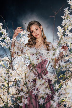 art photo real person beauty face elf girl green eyes, sexy fantasy woman holiday makeup pink lips long loose blonde hair wavy curls white luxury dress spring tree night garden flowers goddess natureの写真素材