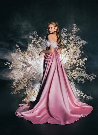 art photo real person beauty face elf woman sitting on flowering throne trees, fantasy girl princess long blonde hair looking back, pink dress spring tree night garden flowers magic light.の写真素材