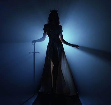 art photo real person fashion model posing, dark silhouette fantasy elf woman queen holds sword in hands. Black room night blue moon light fog. Gothic girl warrior walking with sharp blade shiny dressの写真素材