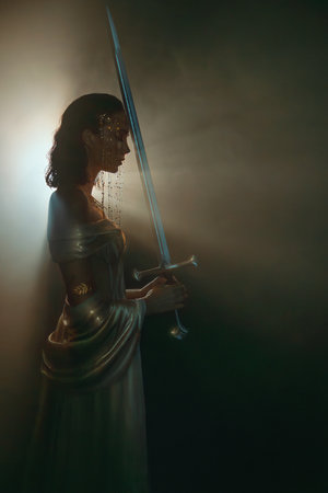 art photo real person fantasy woman queen praying hands holding sword girl in dark room black night castle looking at ray of moon light hope. white golden dress. Elf girl warrior. sharp magic bladeの写真素材