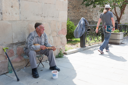 MTSKHETA, GEORGIA- AUGUST 17, 2013: A man with a georgian musical instrument near the walls of the churchのeditorial素材